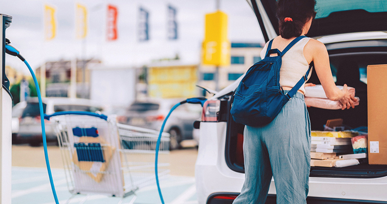 An image of a woman packing her electric vehicle (EV) as it charges after shopping