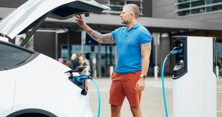A man charging his battery electric vehicle at a charging station.